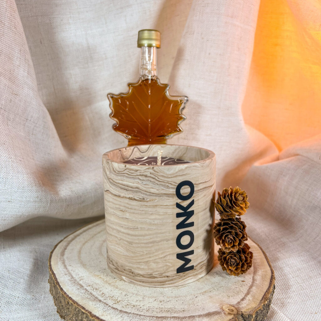 Bougie 300g au sirop d'érable avec en fond une bouteille de sirop d'érable en forme de feuille d'érable