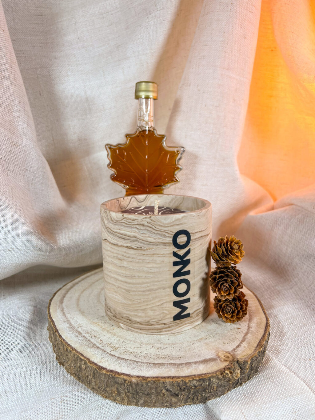 Bougie 300g au sirop d'érable avec en fond une bouteille de sirop d'érable en forme de feuille d'érable