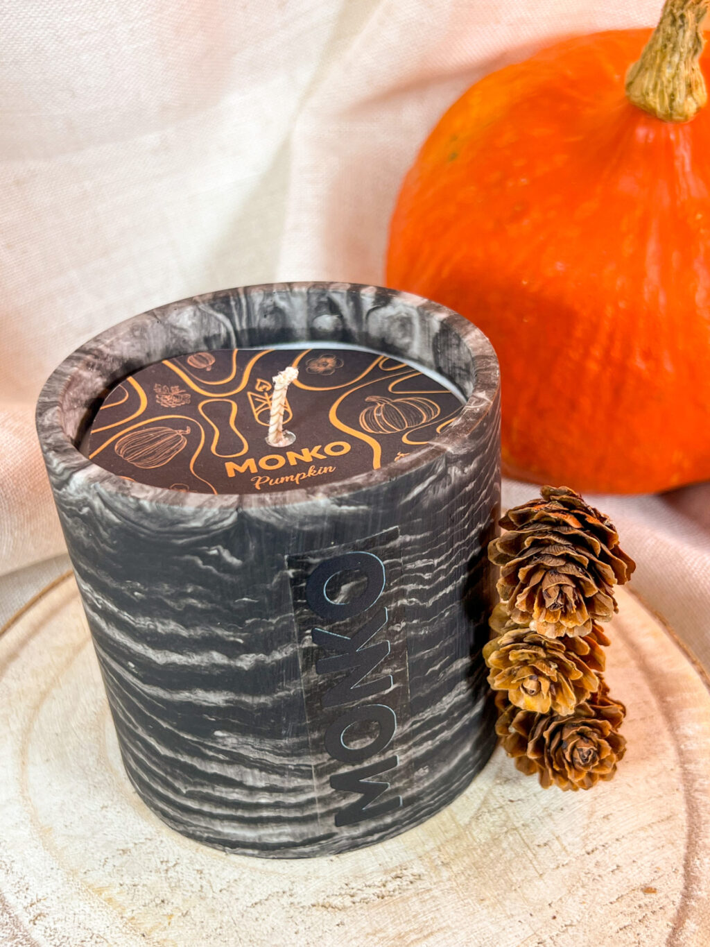 Bougie 300g bougie pumpkin, avec des petites pommes de pin et une citrouille flouté dans le fond, la photo est rapproché pour voir la pastille odeur de la bougie